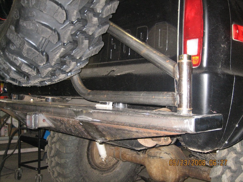 Black truck rear bumper with custom spare tire carrier and large off-road tire