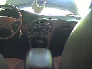 1999 Ford Taurus - The interior of a car is shown, the dashboard and steering wheel, with a SuperMotors logo visible.