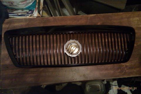 2000 Mercury Grand Marquis - A close-up of a car grille, likely for a Mercury Grand Marquis, rests on a wooden surface.