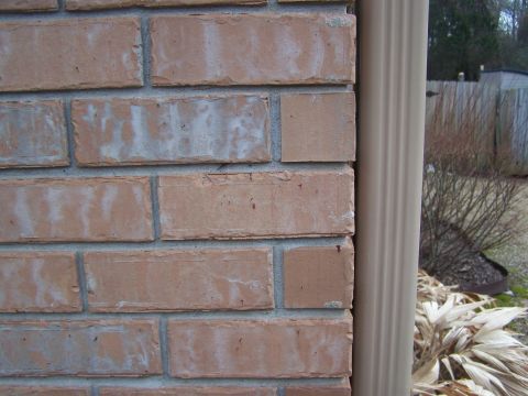 1978 Ford Bronco - A close-up view of a brick wall next to a downspout, with some dry vegetation in the background.