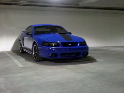 1992 Ford Bronco - A blue Ford Mustang with black racing stripes is parked in a garage.