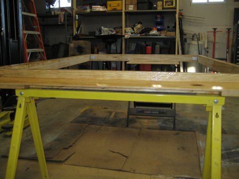 1996 Ford Bronco - A wooden frame is assembled on sawhorses in a workshop setting with shelves and tools in the background.