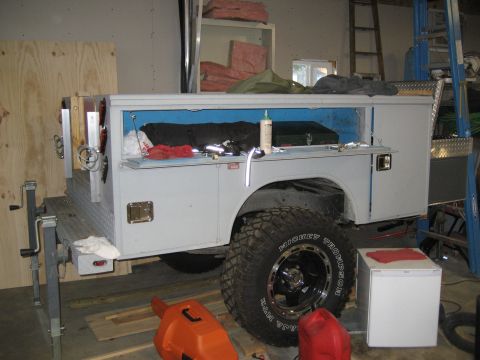 1996 Ford Bronco - A service truck bed is shown with its compartments open, revealing tools and supplies within the garage setting.