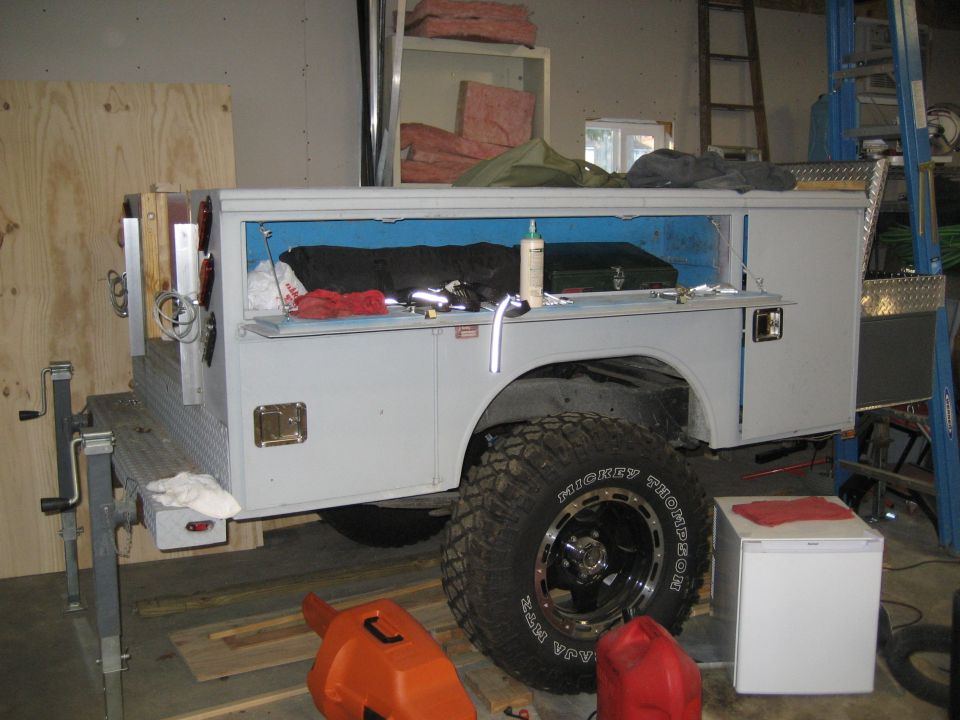 Service truck bed with storage compartments, large off-road tires, and various tools inside