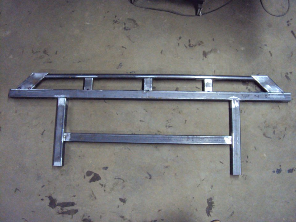 Welded bare steel tubular frame assembly lying on a concrete floor.
