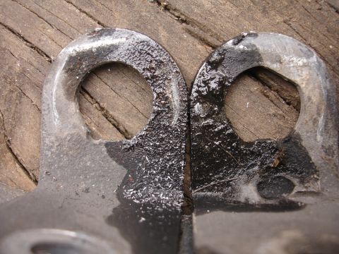 1995 Ford Taurus - Close-up view of two metal brackets with circular openings, positioned on a wooden surface.