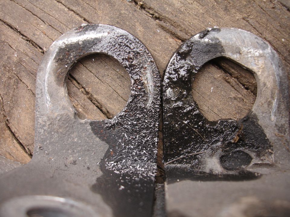 Two metal brackets with circular holes, resting on weathered wood