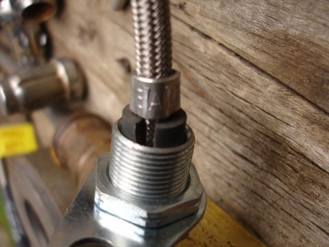 1995 Ford Taurus - A close-up view of a metal fitting connected to a braided hose, with the text 'EAT' visible on a metal collar.