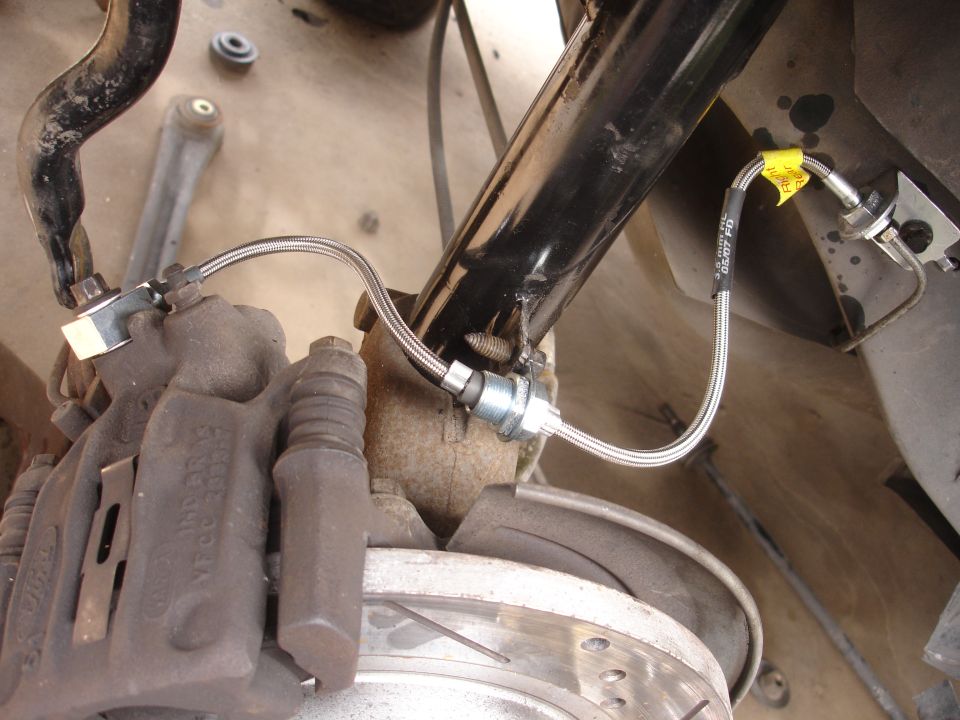 close-up of a car's brake caliper and stainless steel brake line