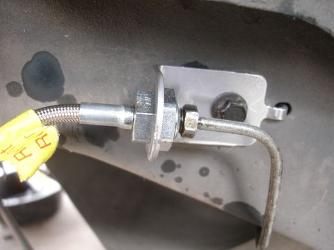 1995 Ford Taurus - Close-up of a brake line fitting and braided hose, attached to a metal bracket.