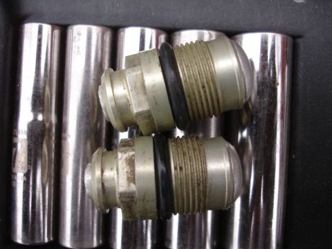 1995 Ford Taurus - Close-up of two metal fittings with O-rings and threaded ends, placed on top of chrome sockets.