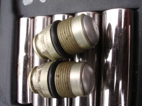 1995 Ford Taurus - Close-up view of two metal valve components, each O-rings and threaded sections, positioned against a backdrop of polished metal rods.