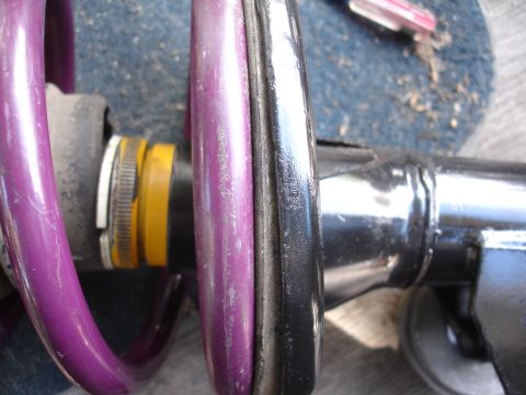1995 Ford Taurus - A close-up view of a vehicle's suspension components, including a purple spring and a yellow adjustment collar.