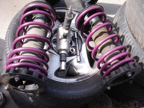 1995 Ford Taurus - Close-up of two aftermarket suspension struts and a pneumatic impact wrench resting on a tire.