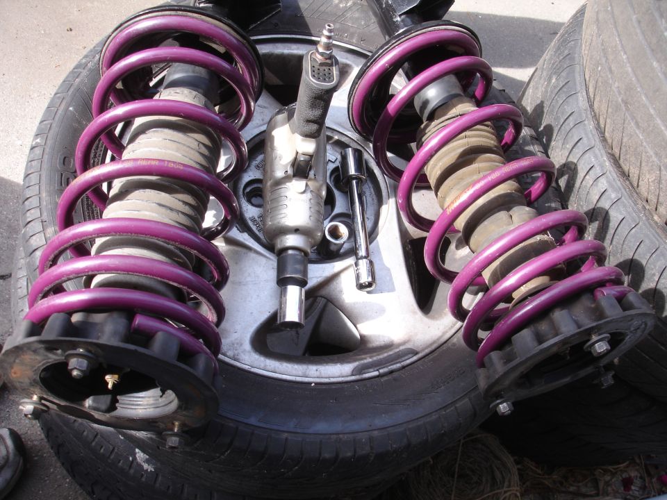 Two purple Eibach/Intrax suspension struts with an impact wrench and socket on a tire