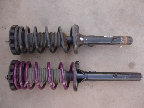 1995 Ford Taurus - Comparison of two suspension struts, one a black spring and the other a purple spring, likely for aftermarket upgrades.
