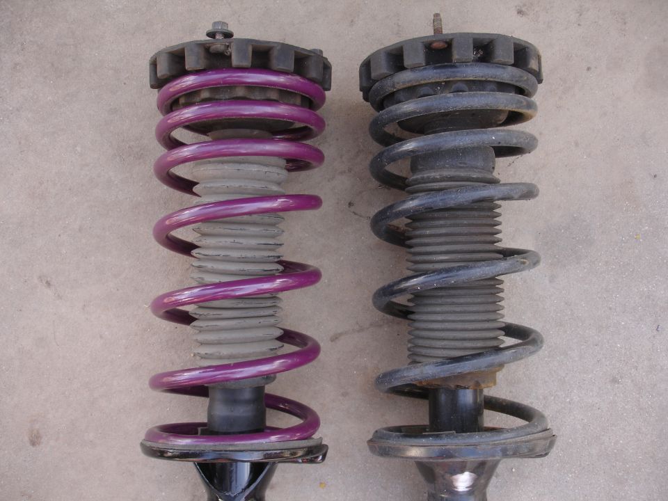 Comparison of two car suspension struts, one with purple springs and one with black springs