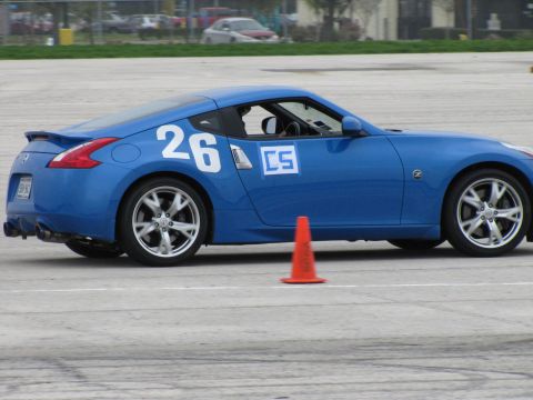2003 Mazda Protege - A blue sports car with racing numbers and logos is seen on a track with an orange cone.