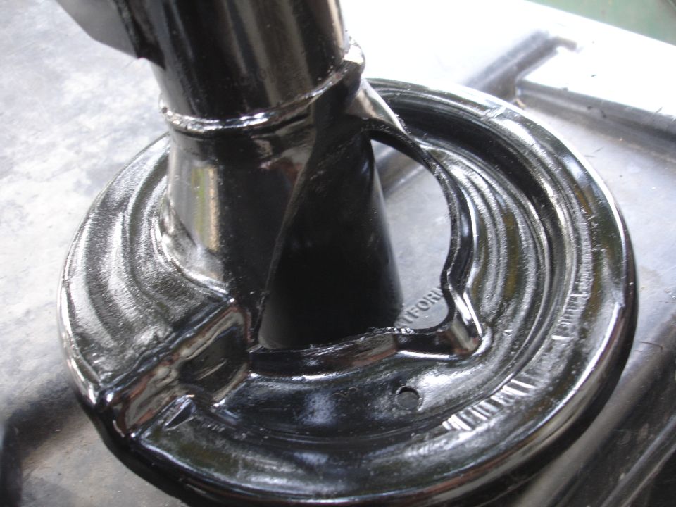 Close-up of a black suspension part with a circular base and a metal arm attached