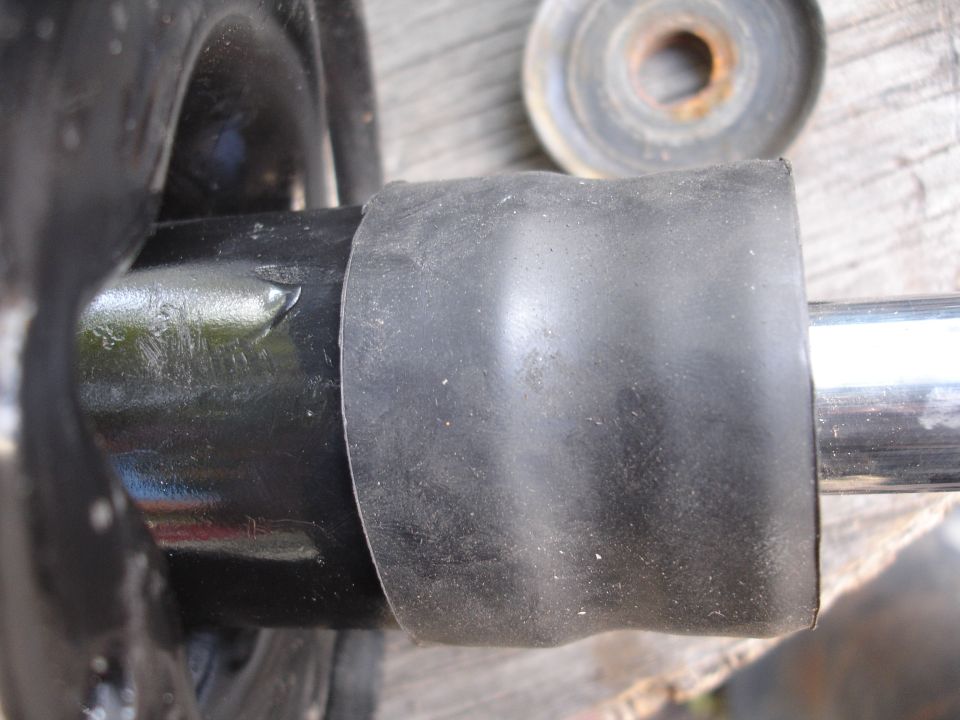 Close-up of a black rubber boot on a metal shaft, possibly part of a car's suspension