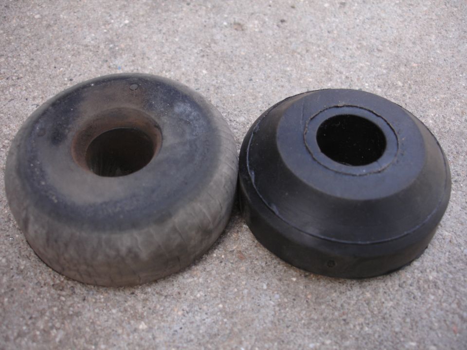 old worn rubber bushing next to a new black rubber bushing, both with center holes