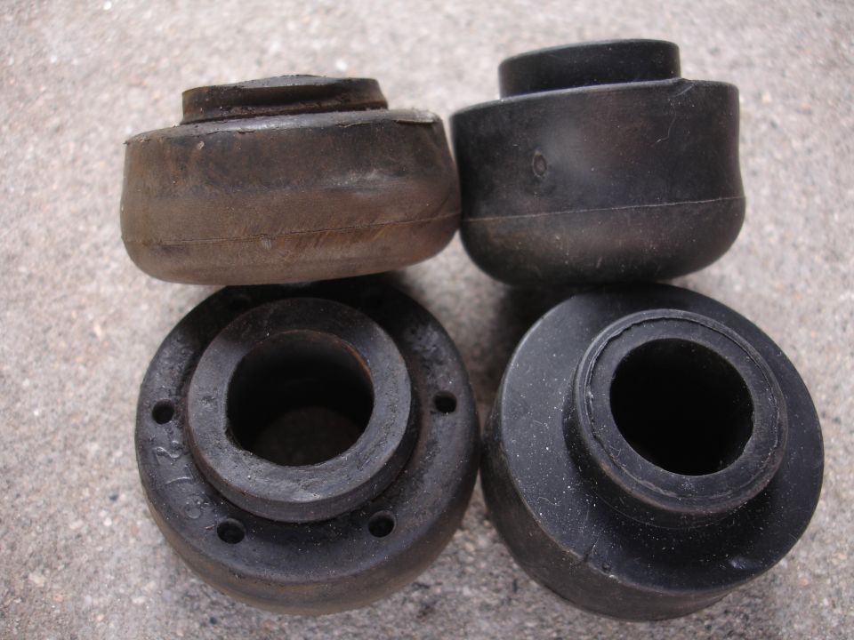four rubber suspension bushings, two in front and two behind, on a concrete surface