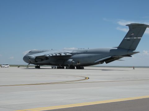 2003 Jeep Wrangler - A C-5 Galaxy military transport aircraft is parked on an airfield tarmac, with a small white van visible in the distance.