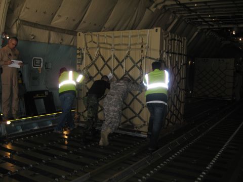 2003 Jeep Wrangler - Inside the cargo bay of a military transport aircraft, four workers in hi-vis vests and camouflage uniforms push a net-strapped cargo palle…