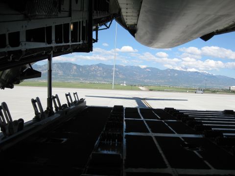 2003 Jeep Wrangler - View out the open rear cargo ramp of a large military transport aircraft, looking past the raised aft fuselage door and roller-conveyor loa…