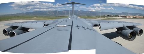 2003 Jeep Wrangler - Stitched panorama shot from atop the fuselage of a gray four-engine military transport aircraft, looking aft along the spine over both swep…
