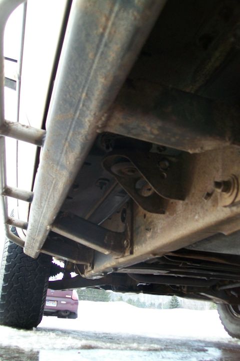 2000 Chevrolet Tahoe - The underside of a vehicle, showing the frame and slider bars, with another car in the distance.