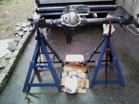 1990 Ford Bronco - A rear axle assembly is supported by jack stands, with a portion of a vehicle visible overhead.