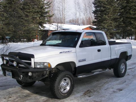 1990 Chevrolet Suburban - This white Dodge Ram 2500 pickup truck is equipped with a heavy-duty bumper and off-road tires, suggesting it is prepared for challenging t…