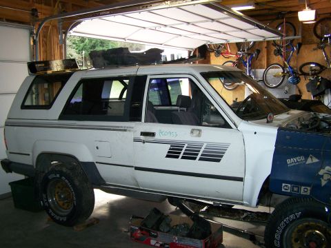 1988 Suzuki Samurai - This white SUV, possibly a 1988 model, is in a garage with its front end disassembled.