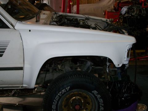 1988 Suzuki Samurai - Front quarter view of a white SUV with its engine exposed, undergoing repairs.