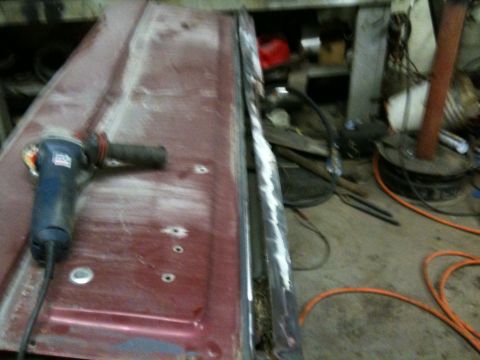 1993 Ford Bronco - A power tool is used to work on a car door in a garage setting.
