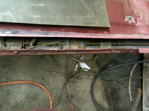 1993 Ford Bronco - The undercarriage of a vehicle displays significant rust and exposed wiring, with a black mesh grate visible.
