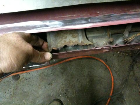 1993 Ford Bronco - A hand inspects a heavily rusted metal panel, revealing significant corrosion.