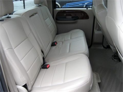 1979 Ford F-150 - The interior of a vehicle shows the rear seating area with beige leather seats and seatbelts.