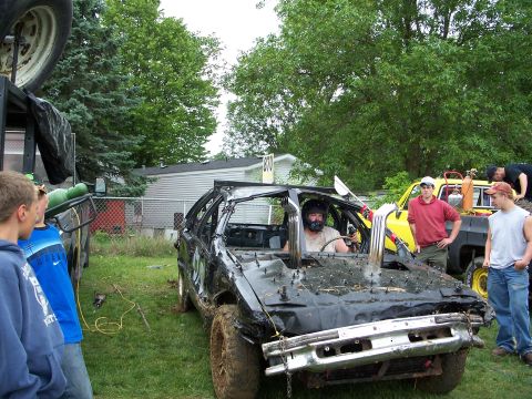 1979 Ford F-250 - A heavily modified car, likely prepared for a demolition derby, sits in a grassy area with spectators nearby.