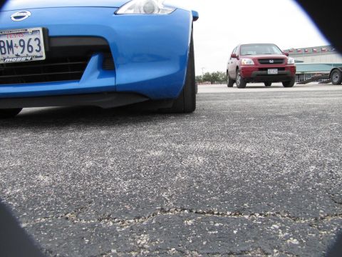 2003 Mazda Protege - A blue sports car is parked on cracked asphalt, with a red SUV in the distance.