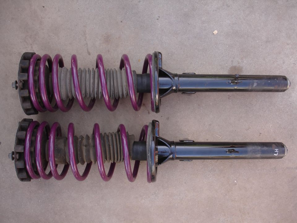 Two purple coilover suspension struts with black dampers, one marked 'LH'
