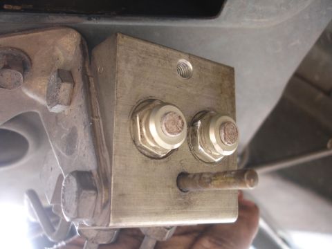 1995 Ford Taurus - A close-up view of a metal bracket assembly with bolts and a protruding rod, likely part of a vehicle's suspension or braking system.