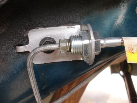1995 Ford Taurus - Close-up of a brake line fitting attached to a metal bracket on a vehicle's chassis.