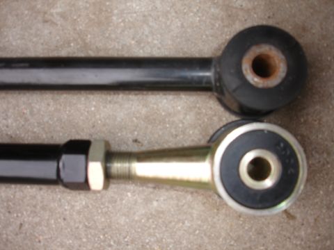 1995 Ford Taurus - Comparison of two suspension control arms, one old and one new, against a concrete surface.