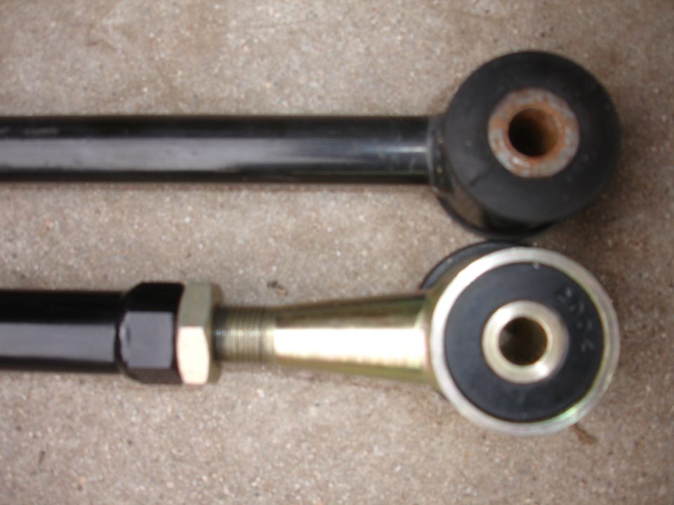Two suspension control arms, one with a worn rubber bushing, the other with a new metal-ended bushing
