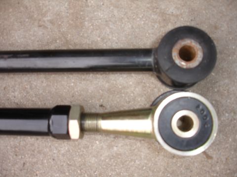 1995 Ford Taurus - Close-up view of two automotive suspension control arms, highlighting their different bushing types and adjustment mechanisms.