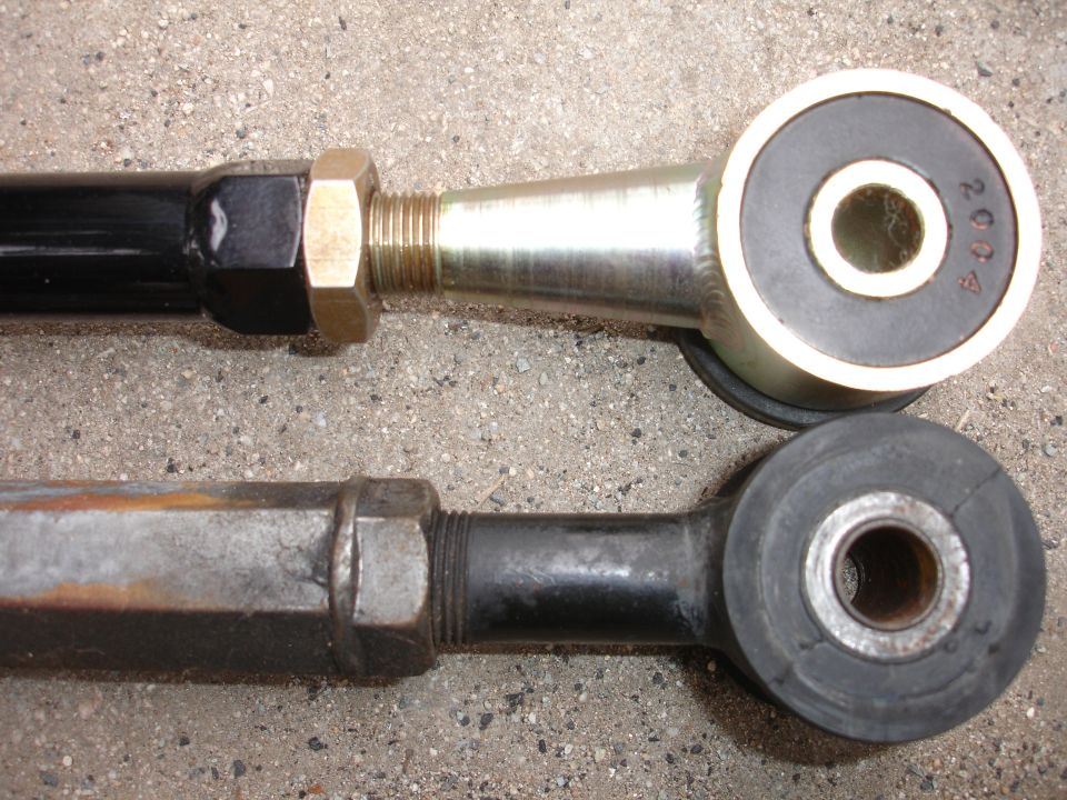 Comparison of two suspension control arms, one new with gold finish and black bushing, the other old and rusted