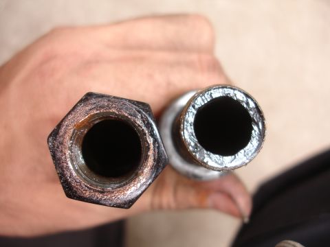 1995 Ford Taurus - Close-up view of two metal components, one threaded and one tubular, held for inspection.