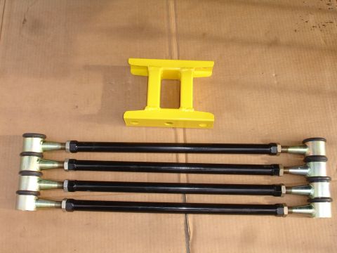1995 Ford Taurus - A set of aftermarket suspension components, including adjustable control arms and a yellow bracket, are displayed on a flat surface.